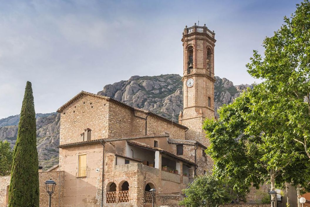 Collbató, pueblo a los pies de Montserrat en el Baix Llobregat
Collbató es un municipio del Baix Llobregat situado literalmente a los pies de la montaña de Montserrat, en la parte más septentrional de la comarca. El término municipal combina el valle de la riera de Can Dalmases con las laderas del macizo, formando un paisaje muy característico donde se mezclan roca, bosque mediterráneo y vistas abiertas hacia el Llobregat. El pueblo se alza a unos 400 metros de altitud y cuenta con alrededor de 4.800 habitantes, lo que le permite mantener un ambiente de villa tranquila, con vida de pueblo y servicios básicos bien repartidos. La autovía A-2 y las carreteras que conectan con Abrera, Esparreguera, Monistrol de Montserrat o El Bruc facilitan la comunicación con el resto del área metropolitana, mientras que el núcleo urbano conserva un centro compacto, calles con pendiente, casas tradicionales y equipamientos que vertebran el día a día de los vecinos. Collbató es, en definitiva, una puerta natural a Montserrat y un lugar donde naturaleza, historia y vida cotidiana van de la mano.