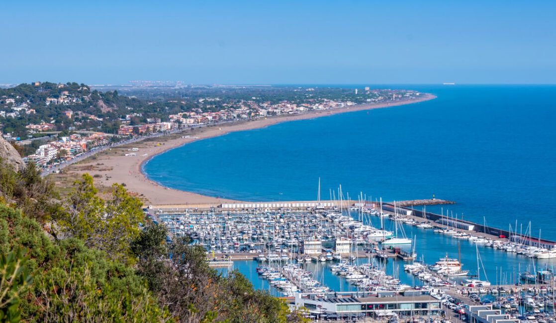 Castelldefels, mar, castillo e identidad propia en el Baix Llobregat
Castelldefels es un municipio costero del Baix Llobregat situado a unos 20–25 km de Barcelona, entre el delta del Llobregat y el macizo del Garraf. Con cerca de 70.000 habitantes y algo menos de 13 km² de superficie, combina una extensa franja de playa con zonas residenciales, un centro urbano vivo y una importante actividad turística y de servicios. La ciudad es conocida por sus más de 5 km de litoral de arena fina, por la silueta del castillo sobre la colina y por su buena conexión por carretera y tren con Barcelona y el aeropuerto. A lo largo del año, Castelldefels ofrece una vida local dinámica, con comercio de proximidad, restauración, equipamientos educativos y deportivos, así como espacios naturales que permiten disfrutar del mar y de la proximidad al Parc del Garraf, convirtiéndola en un lugar atractivo tanto para vivir como para pasar temporadas.